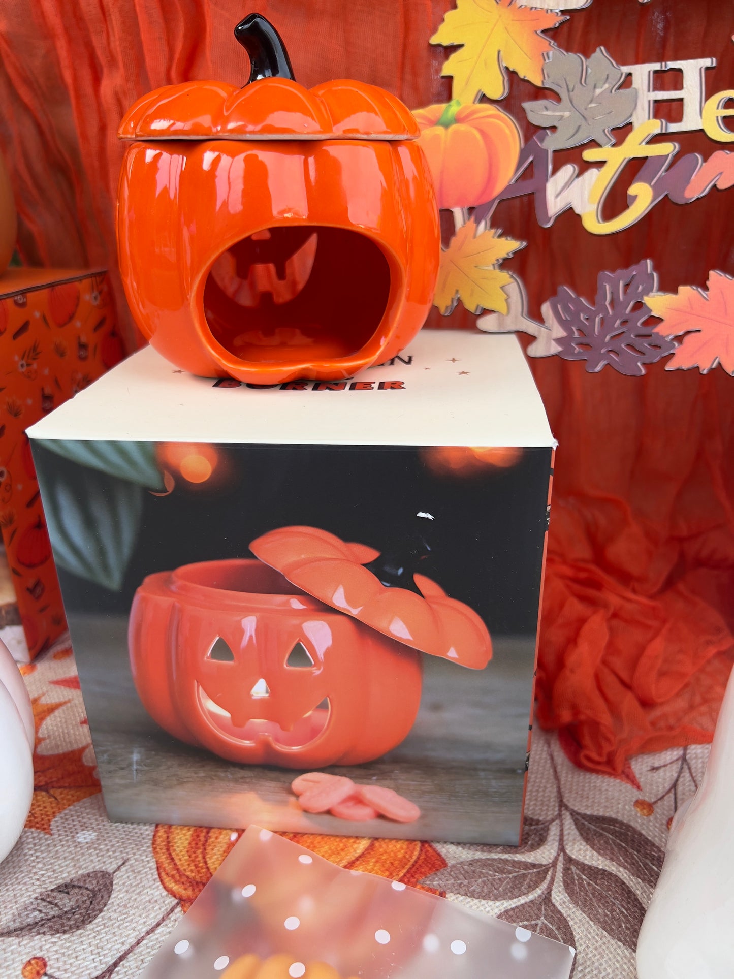Pumpkin-shaped wax melt/oil burner with a leaf design on an orange fabric background