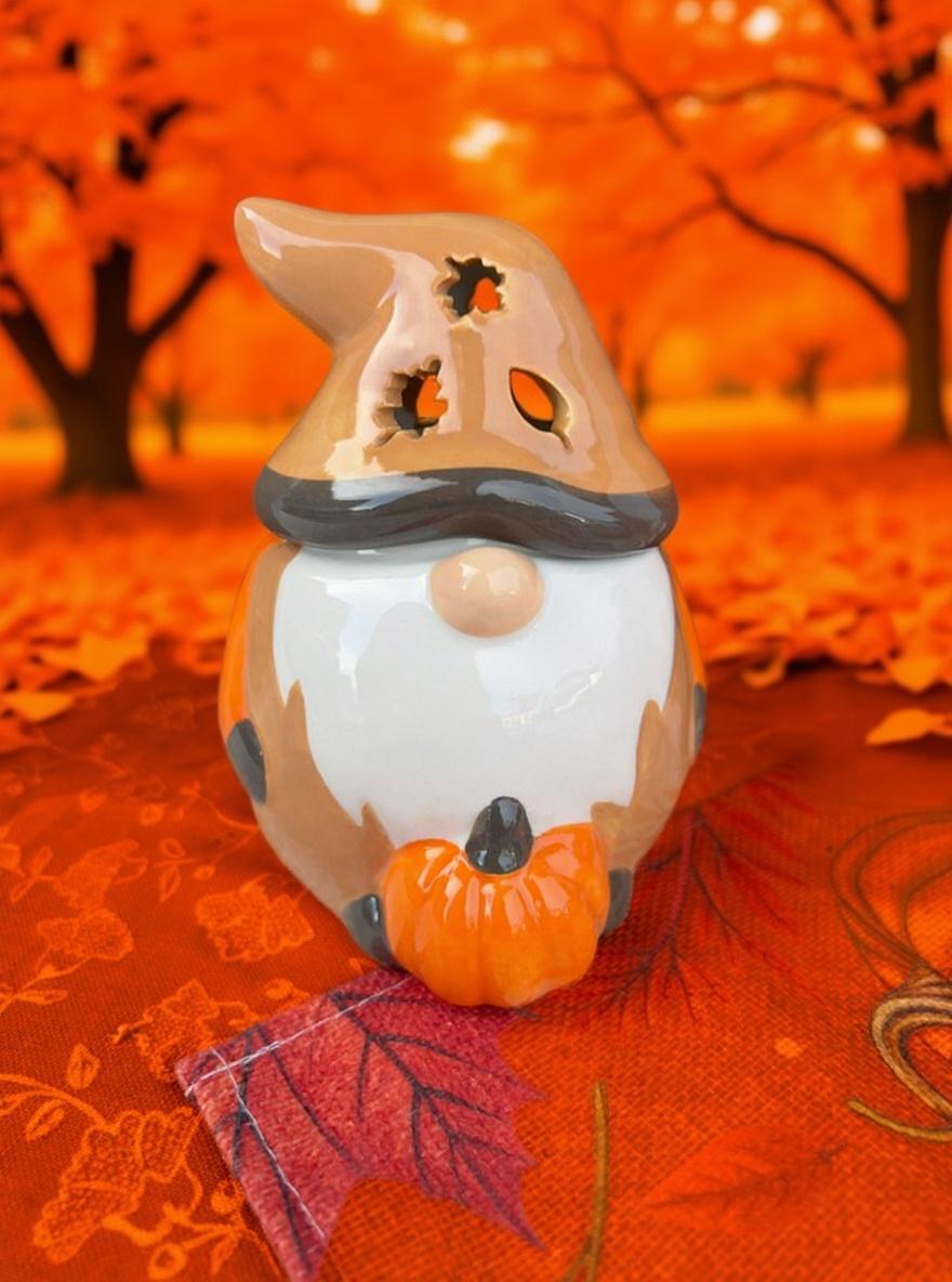Halloween-themed gnome figurine with a witch hat and pumpkin on an autumnal background.