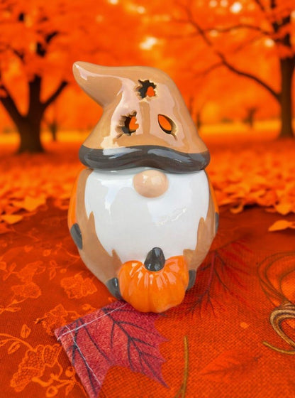 Halloween-themed gnome figurine with a witch hat and pumpkin on an autumnal background.