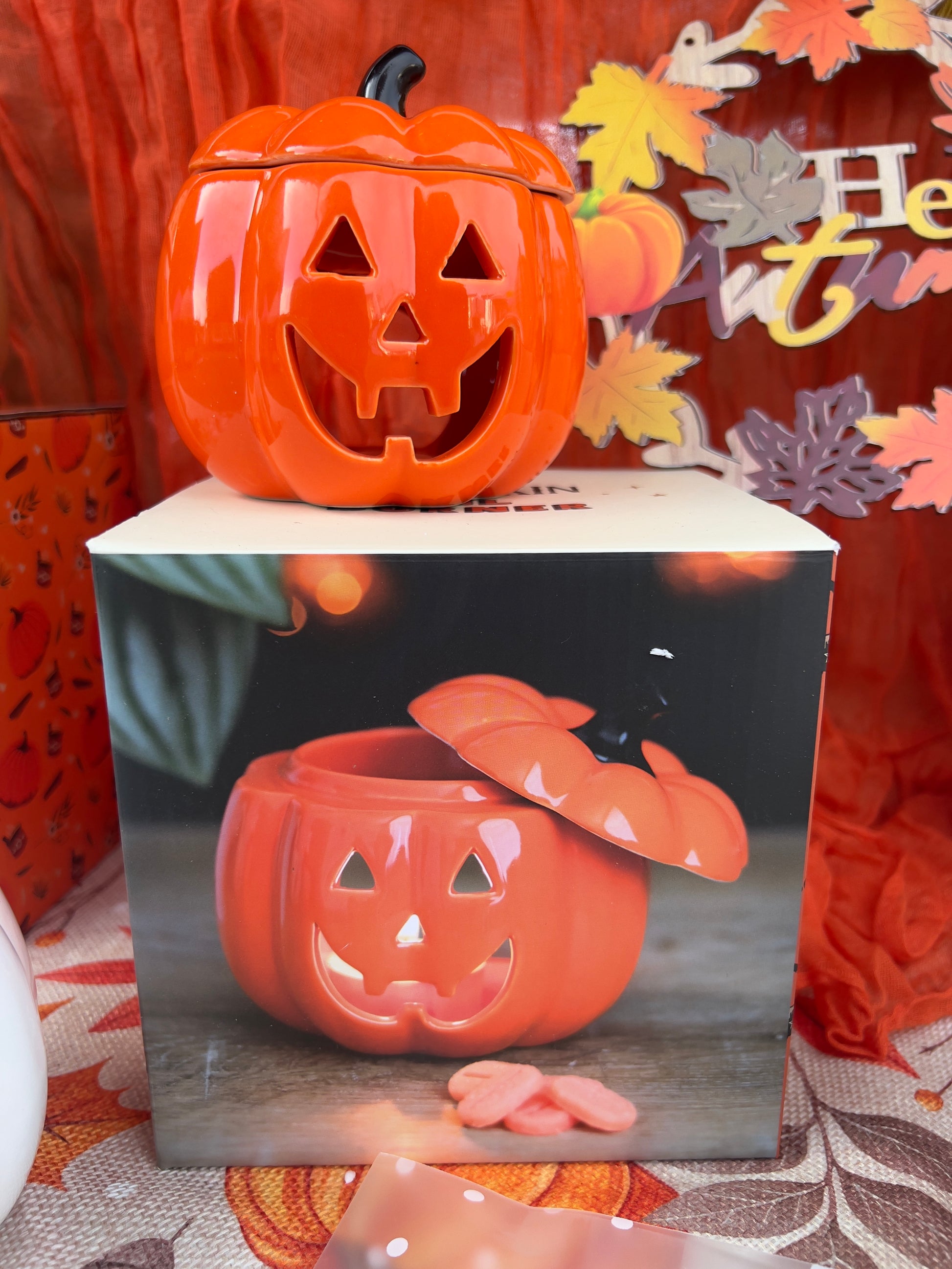 Halloween-themed wax melt/oil burner with pumpkin design on a decorative background
