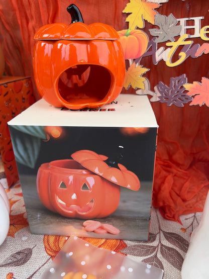 Pumpkin-shaped wax melt/oil burner with a leaf design on an orange fabric background