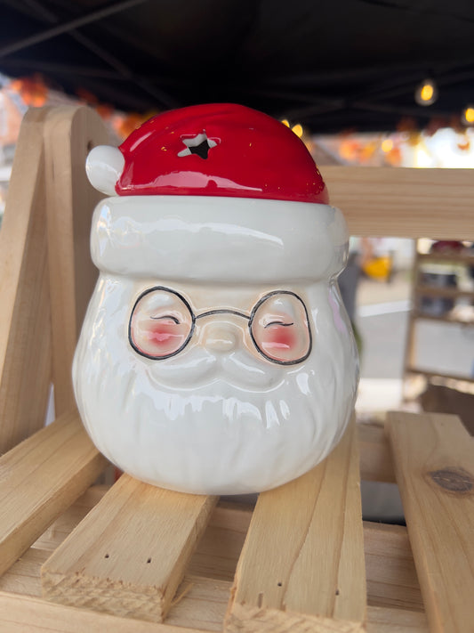 Ceramic Santa Claus wax melt and oil burner with red hat and glasses on a natural wooden display, perfect for Christmas home decor.