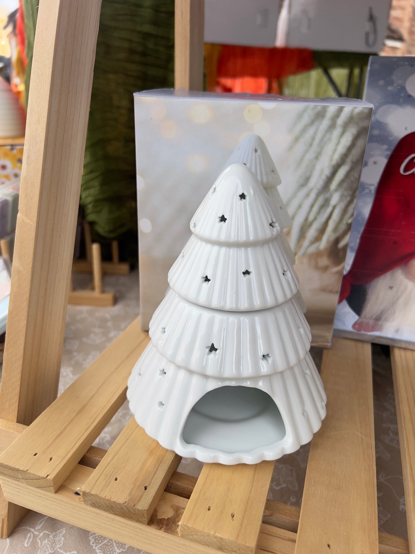 Minimalist white ceramic Christmas tree wax melt burner displayed on a wooden shelf with festive accents.